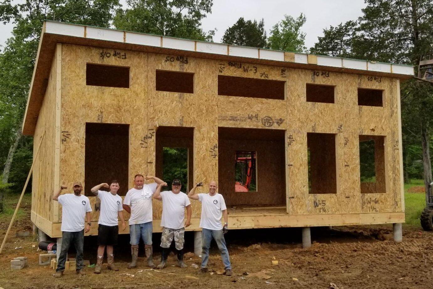 Diy work crew celebrates the completion of the wall and roof panels.