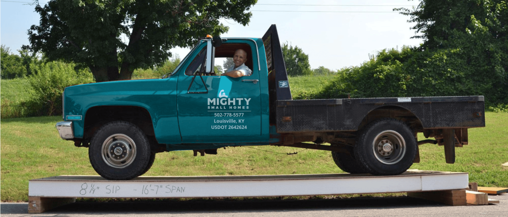 green mighty small homes truck parked on a structural panel