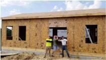 Some workers standing in the door frame of a house as it is in progress of being built