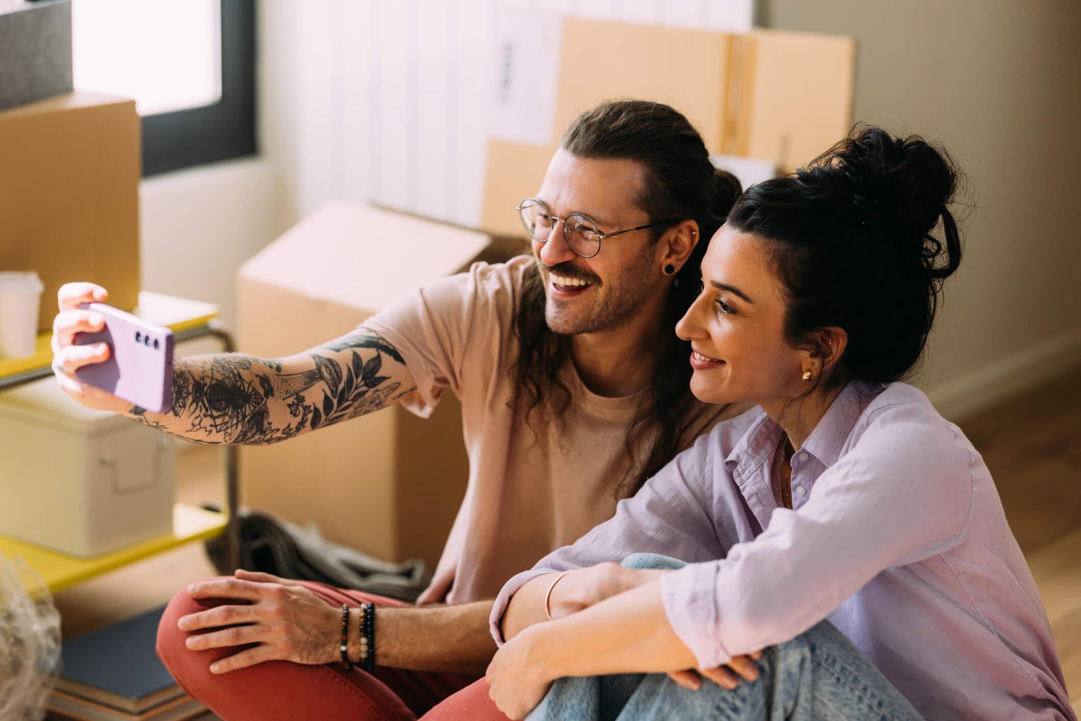 Millennial couple takes a selfie while moving into home