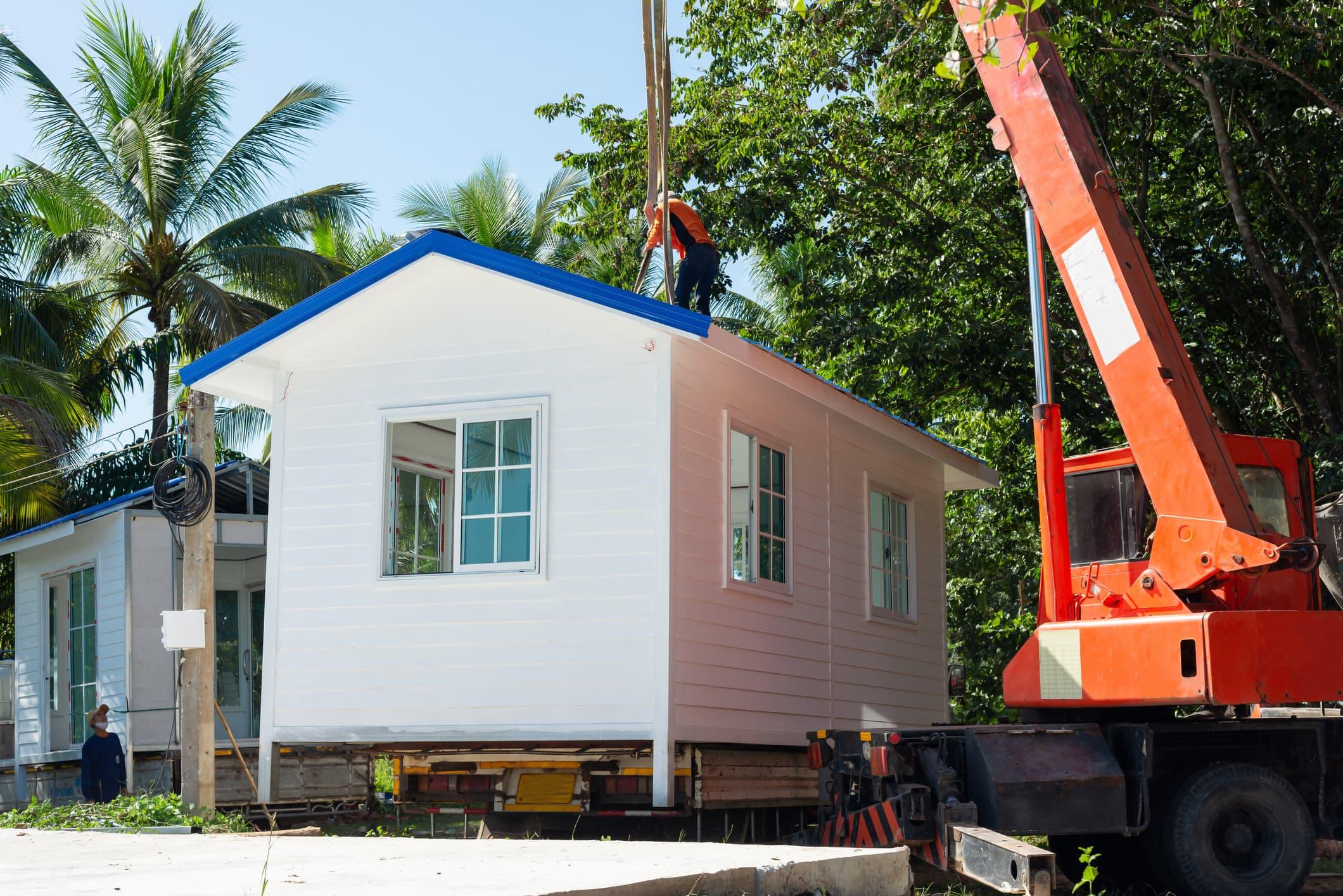 modular home section being lifted into place by crane during on-site installation, highlighting transport, delivery, and placement requirements
