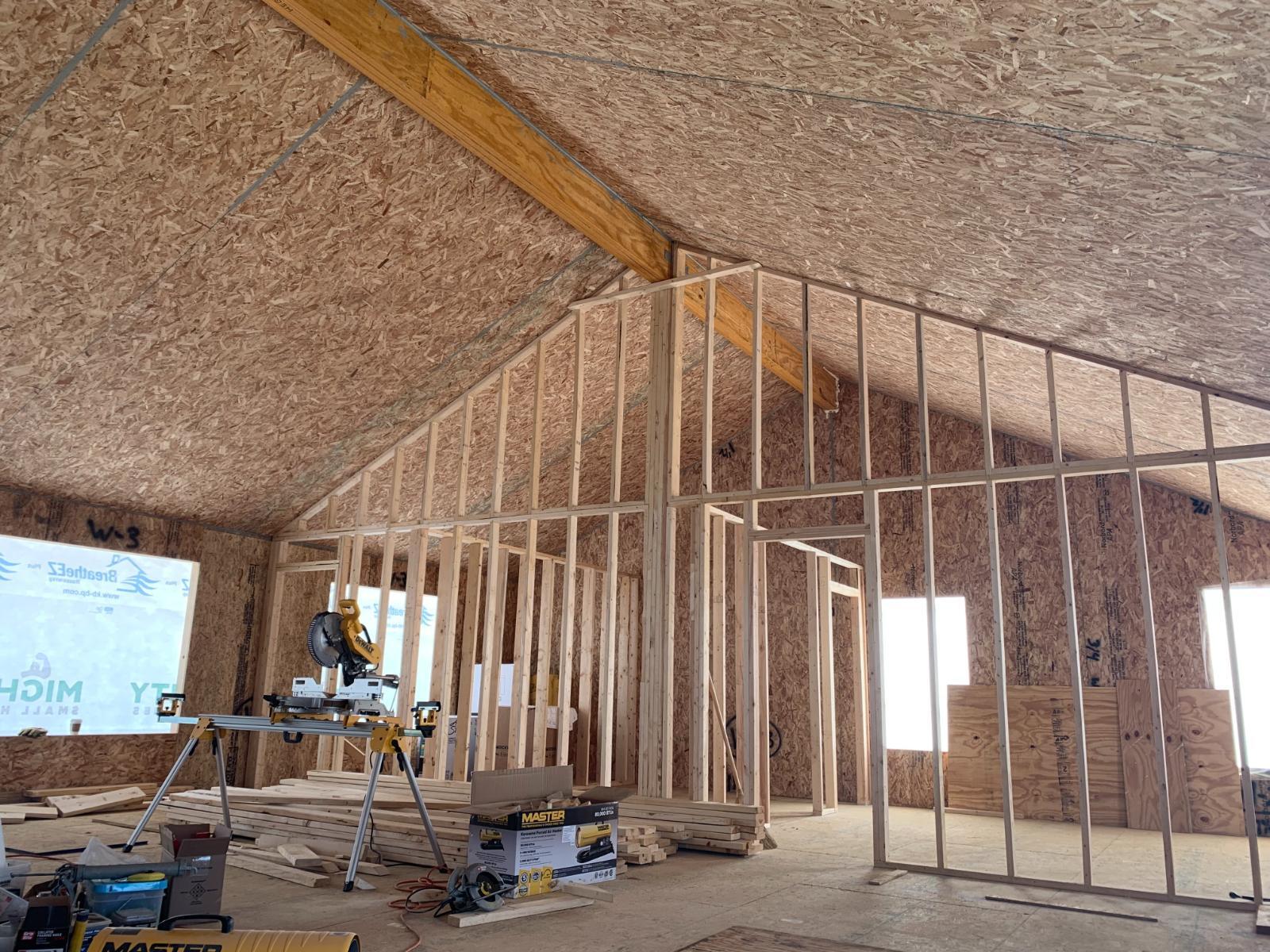 An interior view showing roof beams and wall framing in progress.