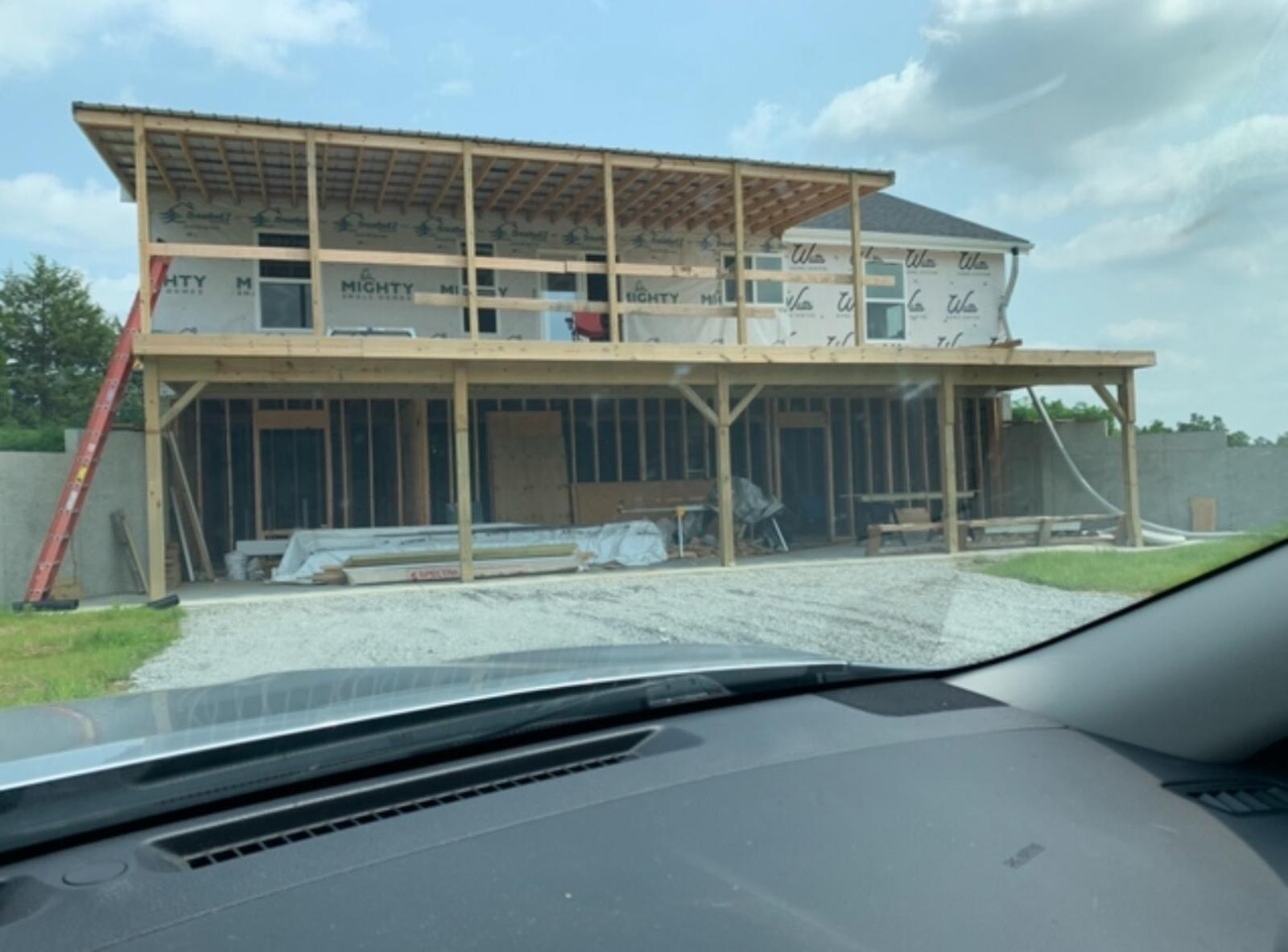 A rear view of the house under construction, featuring a deck and walkout basement.