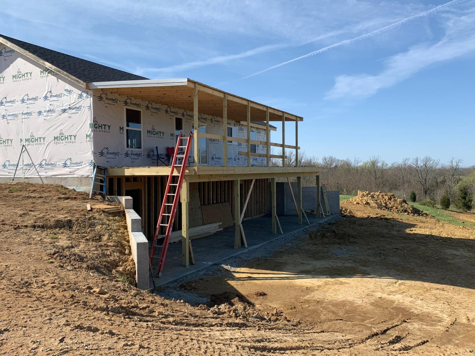 A side view of the house showing exterior sheathing, roof, and a covered porch area.